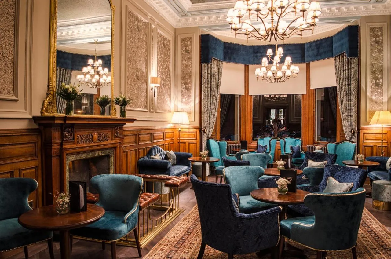 a waiting room with blue chairs and a fireplace at The Bonham in Edinburgh